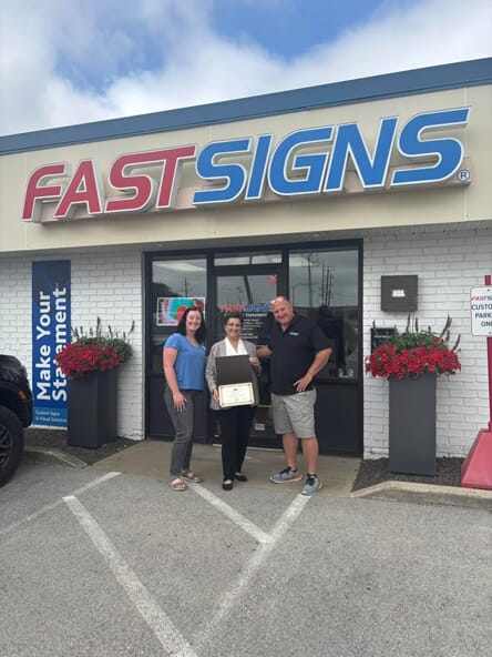 An image of Dave and Sonya Comer with Rep. Haas outside of their FASTSIGNS center.